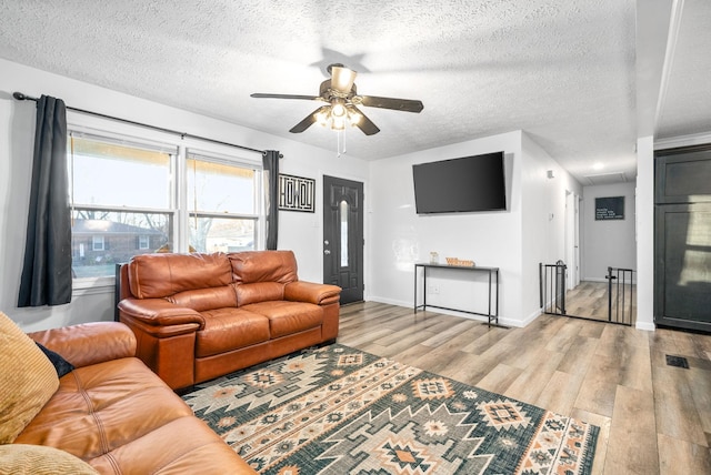 living room with a textured ceiling, light wood-type flooring, and ceiling fan