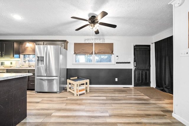 kitchen featuring ceiling fan, sink, stainless steel refrigerator with ice dispenser, crown molding, and light wood-type flooring