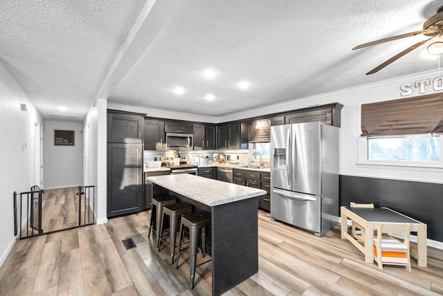 kitchen with a center island, sink, stainless steel appliances, a kitchen breakfast bar, and a textured ceiling