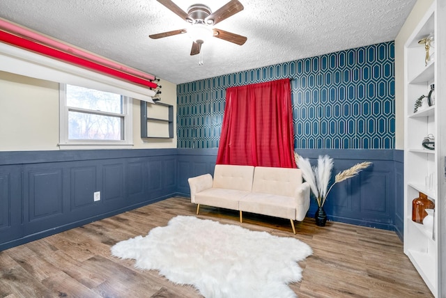 sitting room featuring ceiling fan, wood-type flooring, and a textured ceiling