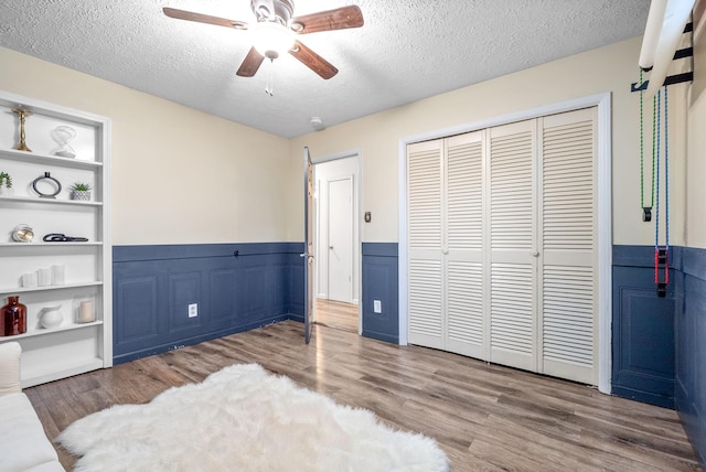 bedroom featuring hardwood / wood-style flooring, ceiling fan, a textured ceiling, and a closet