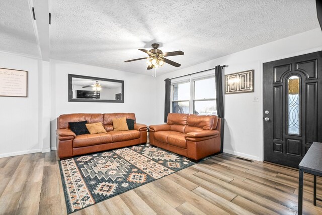 living room featuring ceiling fan, a textured ceiling, and light hardwood / wood-style flooring