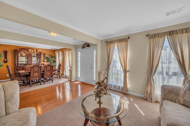 living room featuring plenty of natural light, light hardwood / wood-style flooring, a chandelier, and ornamental molding