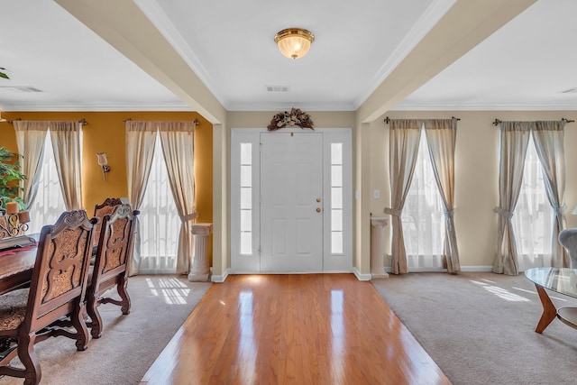 carpeted entryway with a healthy amount of sunlight and ornamental molding