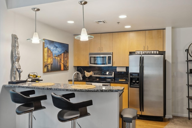 kitchen with kitchen peninsula, appliances with stainless steel finishes, backsplash, and pendant lighting