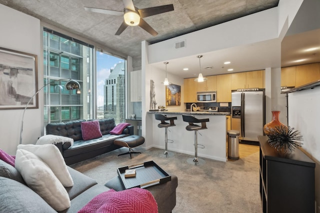 carpeted living room with ceiling fan and sink