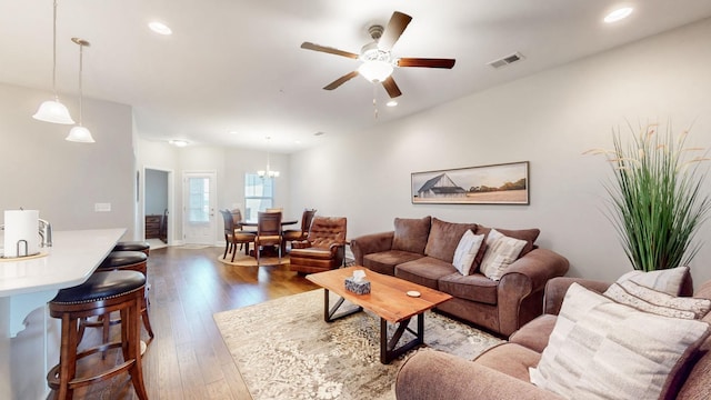 living room with hardwood / wood-style floors and ceiling fan with notable chandelier