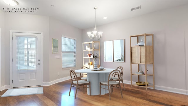 dining space featuring hardwood / wood-style flooring, a healthy amount of sunlight, and a notable chandelier