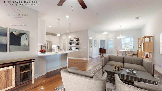 living room featuring hardwood / wood-style flooring, sink, and ceiling fan with notable chandelier