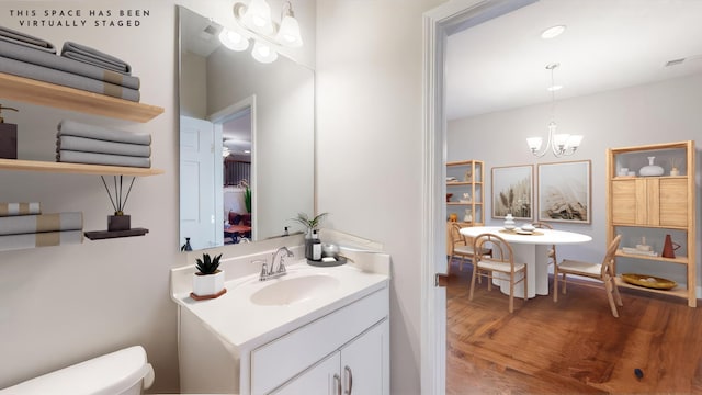 bathroom featuring vanity, a chandelier, and toilet