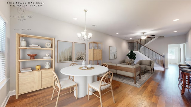 dining space with hardwood / wood-style flooring and ceiling fan with notable chandelier