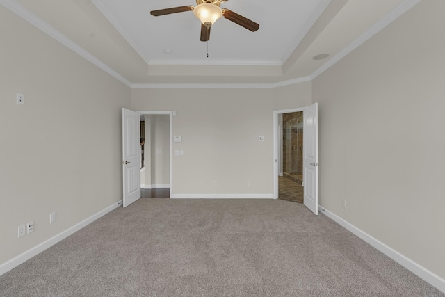 unfurnished room with carpet, ceiling fan, a raised ceiling, and crown molding