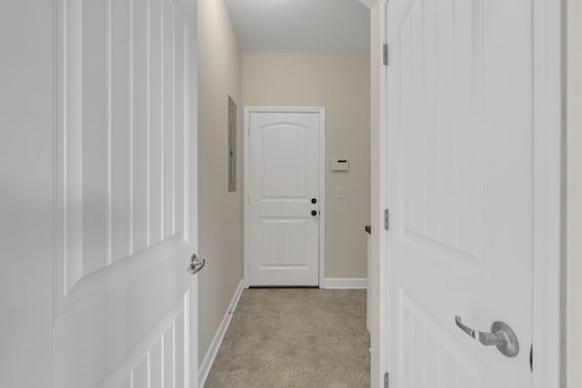 hallway featuring light colored carpet and electric panel