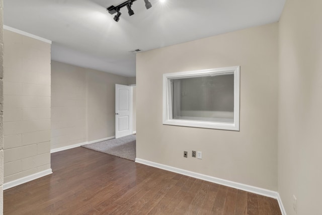 empty room featuring rail lighting and dark hardwood / wood-style floors