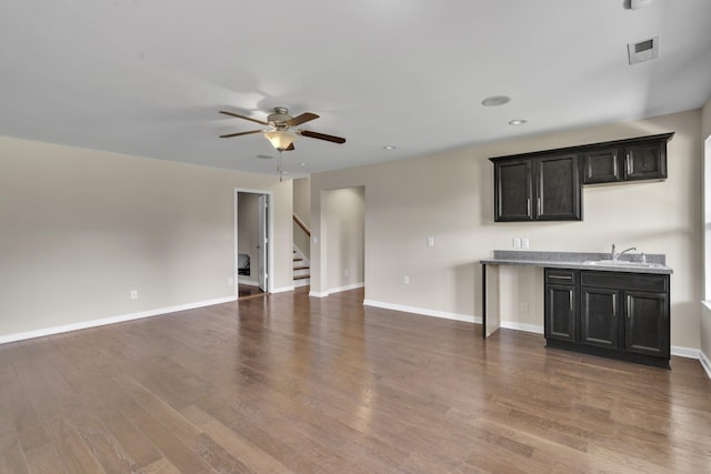 unfurnished living room featuring ceiling fan, sink, and dark wood-type flooring