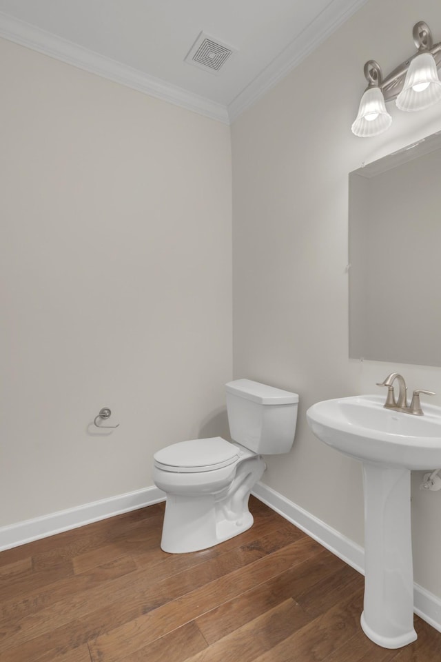 bathroom featuring crown molding, hardwood / wood-style floors, sink, and toilet