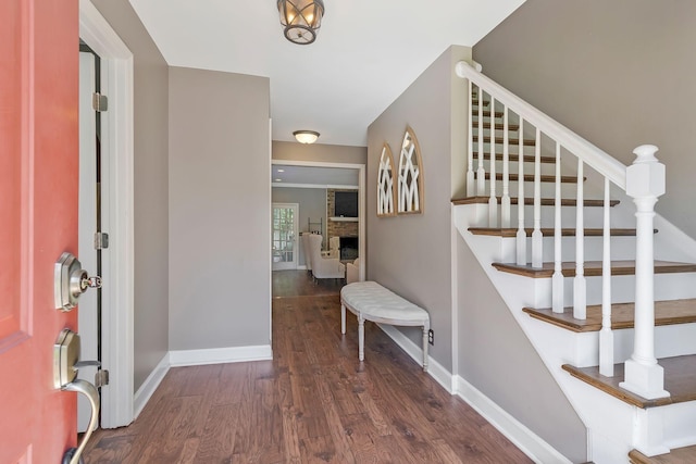 entryway featuring a stone fireplace and dark wood-type flooring