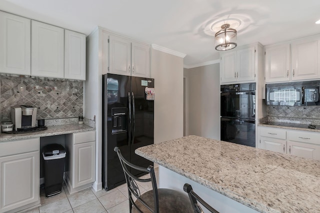 kitchen featuring decorative backsplash, white cabinetry, light stone countertops, and black appliances