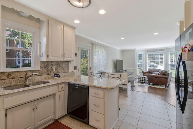 kitchen featuring black appliances, sink, light stone countertops, light tile patterned floors, and kitchen peninsula