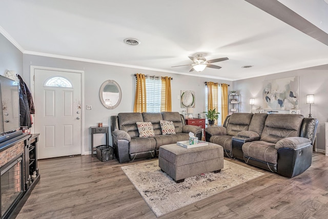 living room with wood-type flooring, ceiling fan, and ornamental molding