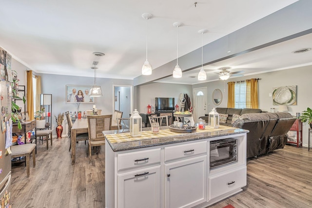 kitchen featuring white cabinets, ceiling fan, black microwave, and hanging light fixtures