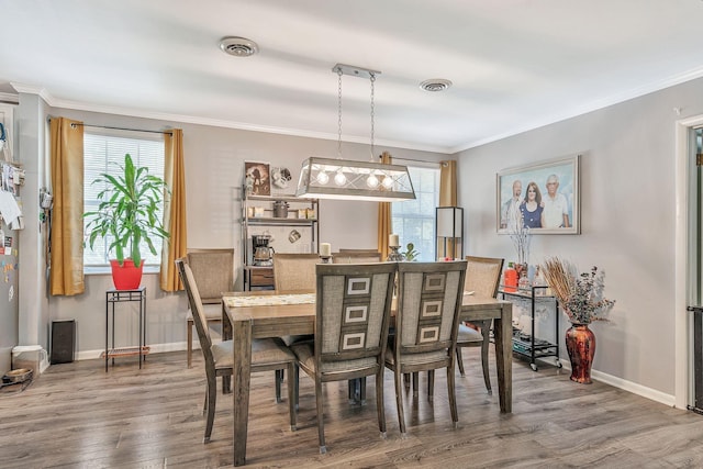 dining space with a wealth of natural light, crown molding, and wood-type flooring