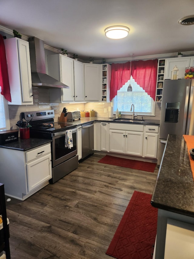 kitchen with wall chimney exhaust hood, stainless steel appliances, sink, white cabinetry, and hanging light fixtures