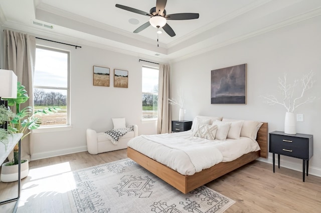 bedroom with a raised ceiling, ceiling fan, and light hardwood / wood-style flooring