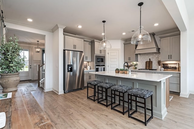 kitchen featuring a kitchen breakfast bar, gray cabinetry, custom exhaust hood, and appliances with stainless steel finishes