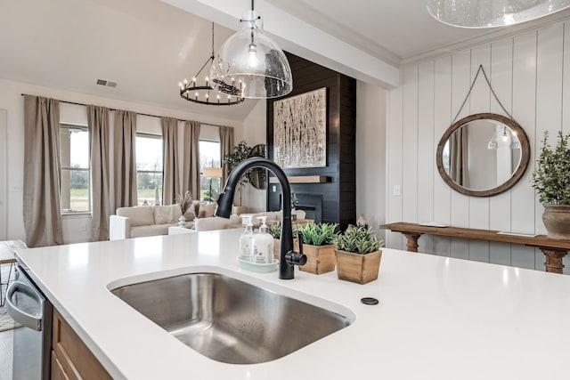 kitchen featuring dishwasher, sink, wooden walls, decorative light fixtures, and a chandelier