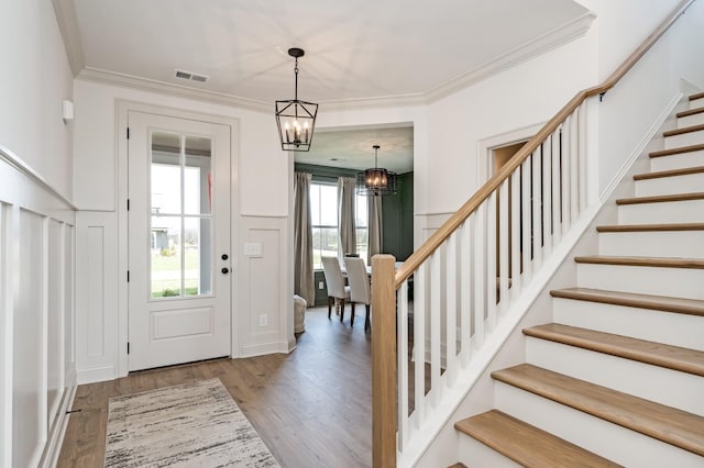 entryway featuring hardwood / wood-style floors, ornamental molding, and a chandelier