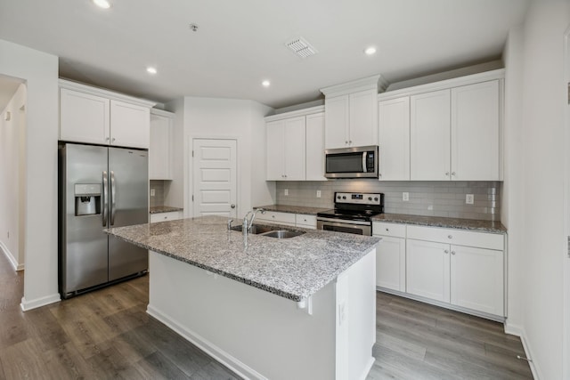 kitchen featuring a kitchen island with sink, white cabinets, sink, light stone countertops, and appliances with stainless steel finishes