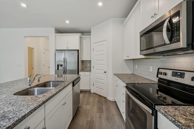 kitchen featuring sink, appliances with stainless steel finishes, stone countertops, white cabinetry, and wood-type flooring