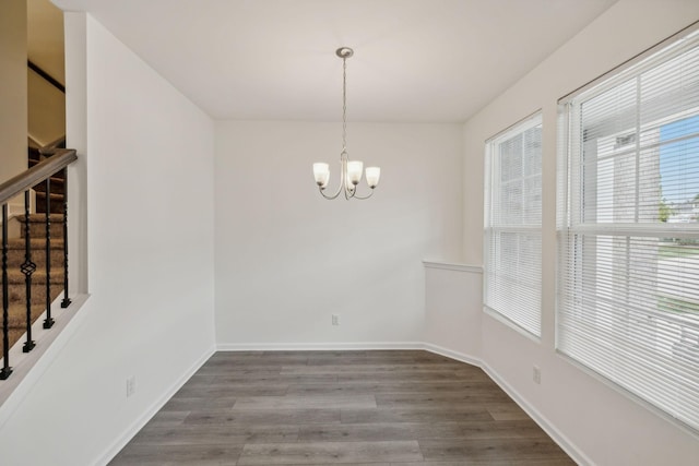 unfurnished dining area featuring dark wood-type flooring and a chandelier