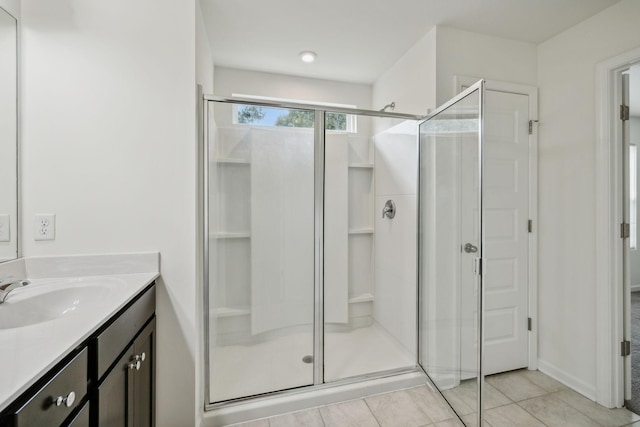 bathroom with tile patterned flooring, vanity, and walk in shower