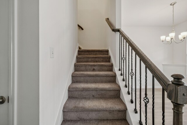 staircase with hardwood / wood-style flooring and a notable chandelier