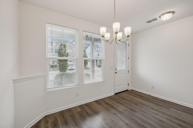 unfurnished dining area featuring dark wood-type flooring and a notable chandelier