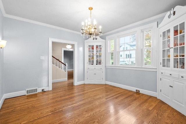 unfurnished dining area featuring hardwood / wood-style flooring, an inviting chandelier, and crown molding