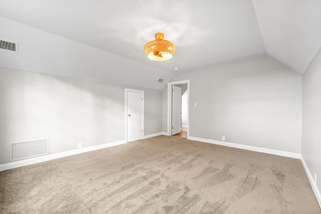 carpeted empty room with vaulted ceiling