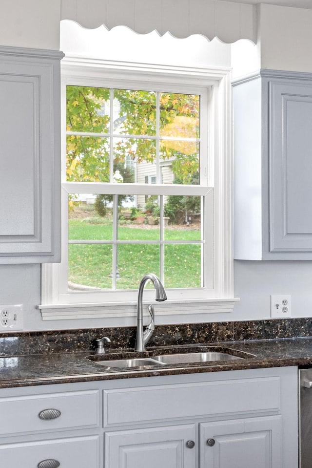 room details featuring white cabinetry, dark stone counters, and sink