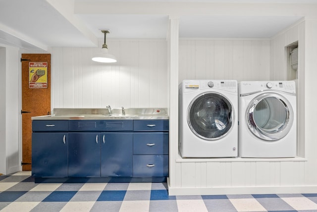 laundry area featuring washer and dryer, wood walls, and sink