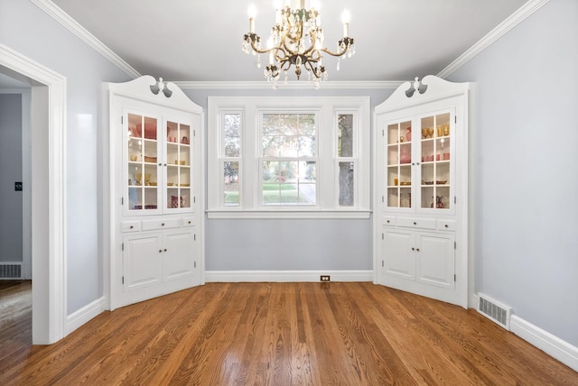 unfurnished dining area featuring hardwood / wood-style floors, a notable chandelier, and crown molding