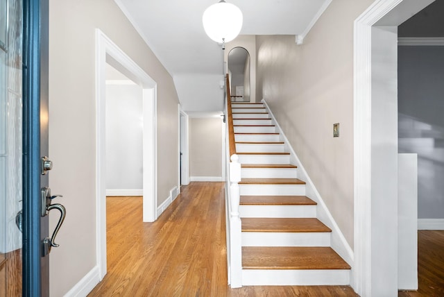 stairway with hardwood / wood-style floors and crown molding