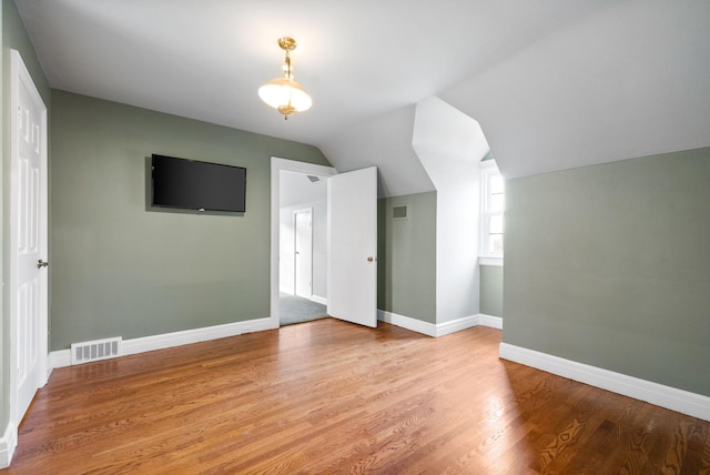 additional living space featuring light hardwood / wood-style floors and lofted ceiling