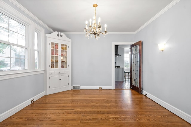 unfurnished dining area with dark hardwood / wood-style flooring, an inviting chandelier, and crown molding