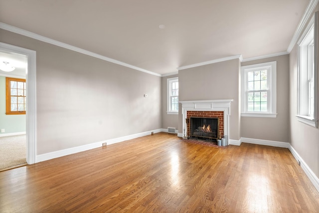 unfurnished living room with ornamental molding, light wood-type flooring, and a brick fireplace