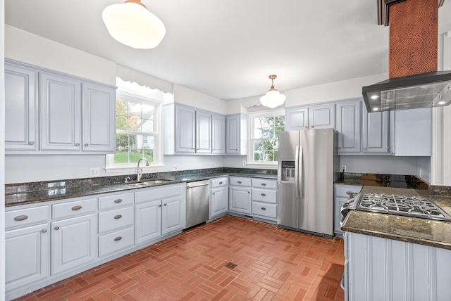 kitchen featuring stainless steel appliances, a healthy amount of sunlight, sink, wall chimney range hood, and pendant lighting