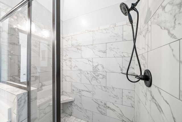 bathroom featuring a tile shower and a textured ceiling