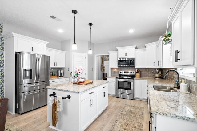 kitchen featuring white cabinets, sink, decorative light fixtures, a kitchen island, and stainless steel appliances