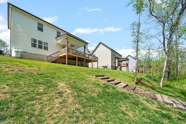 back of house featuring a wooden deck, ceiling fan, and a yard